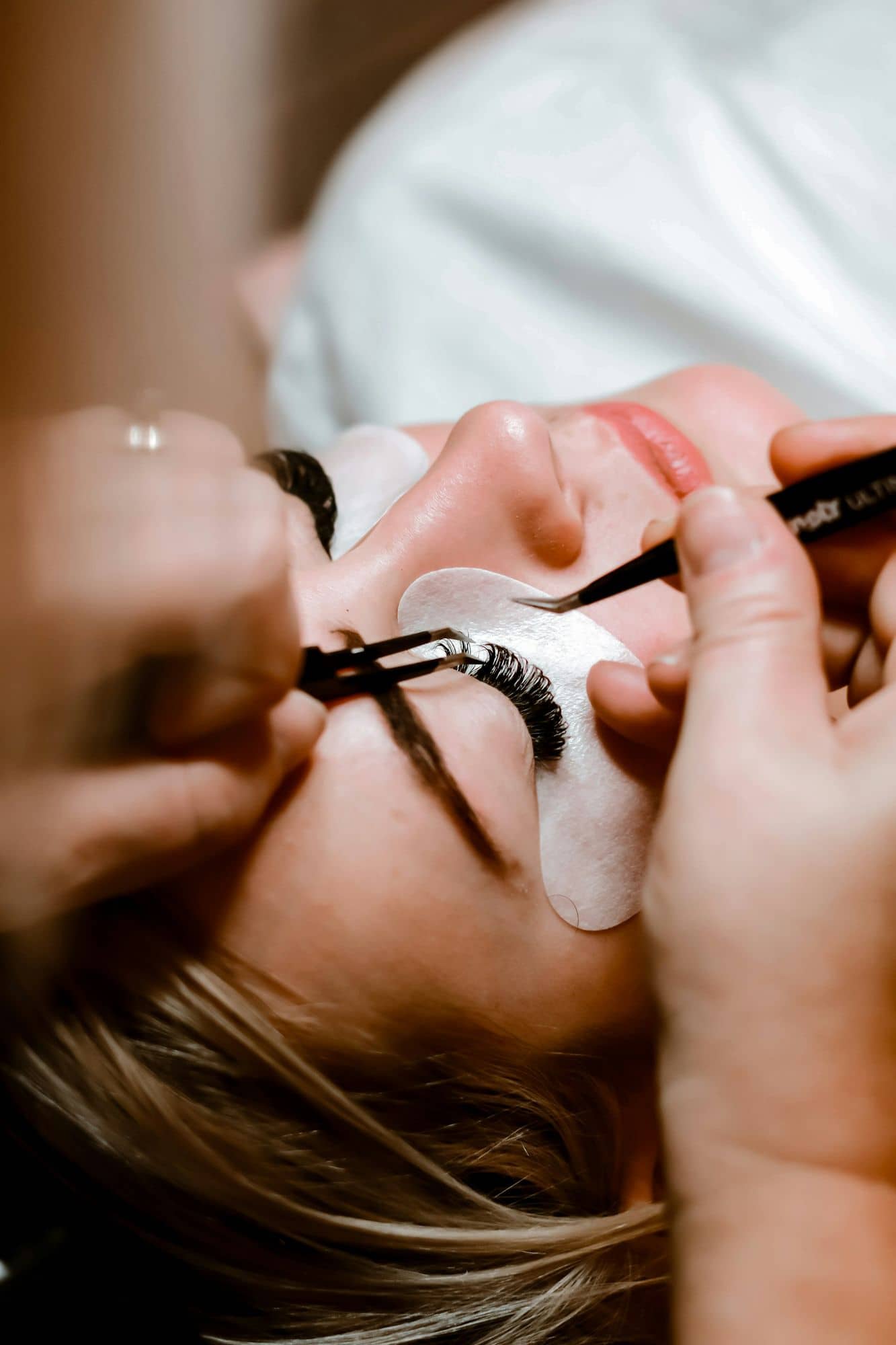 Lash artist placing a classic extension with fine tweezers
