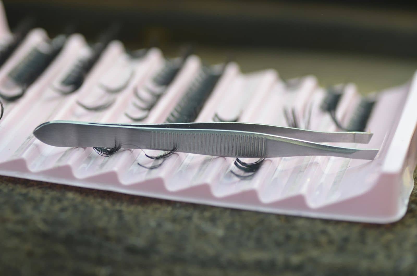 Tweezers resting on a tray of lash extensions